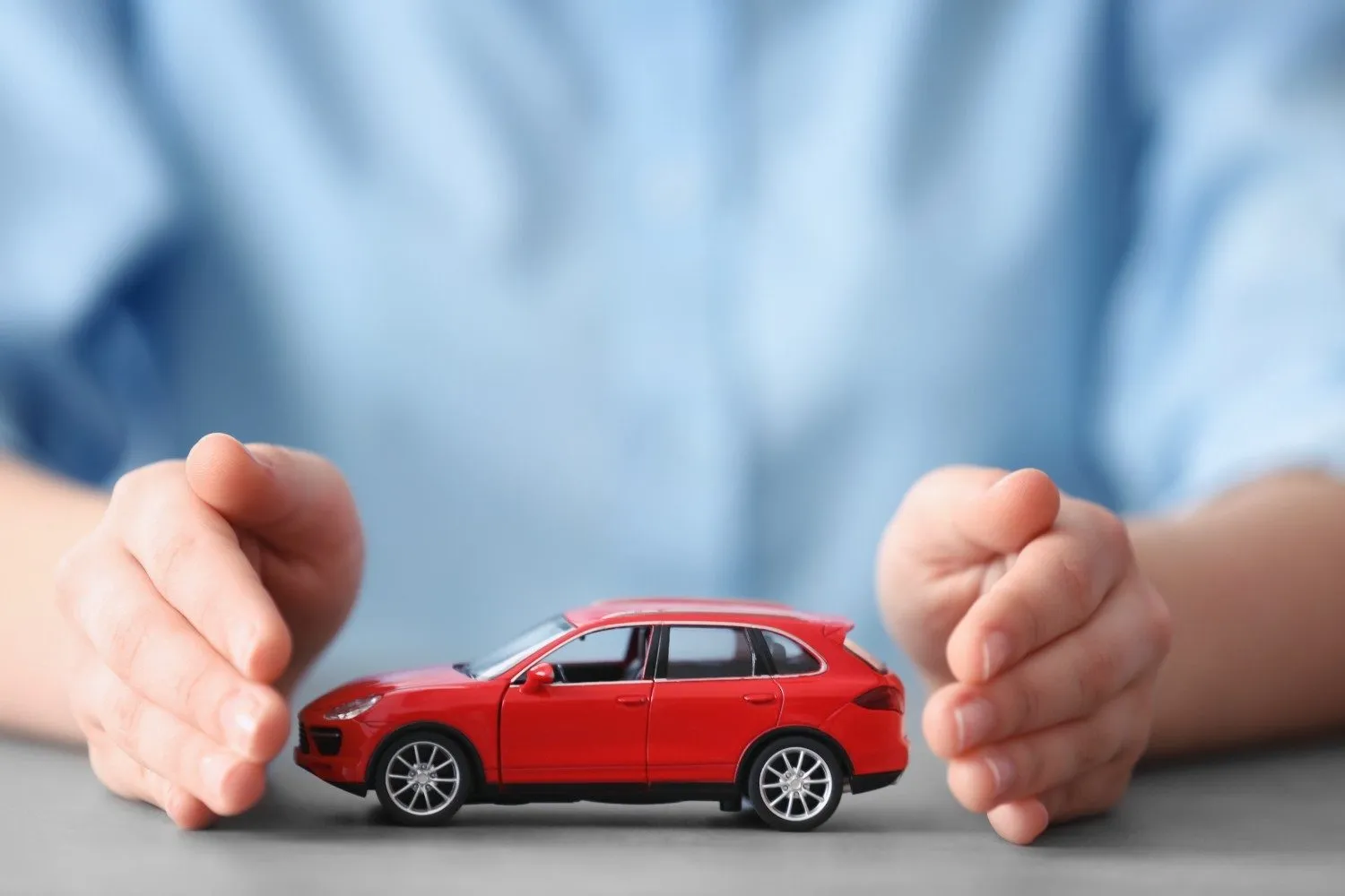 Two hands cupped around a model car